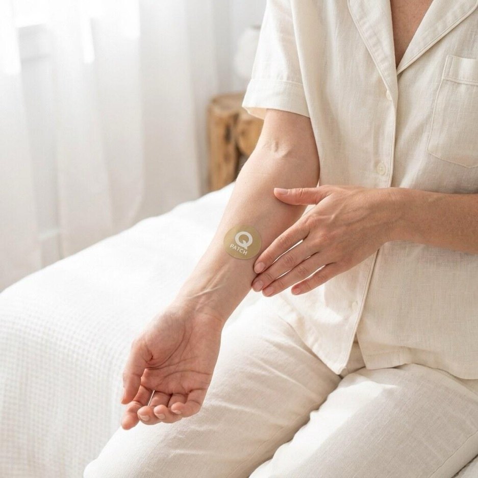 Person in linen loungewear sitting on a bed, touching their forearm